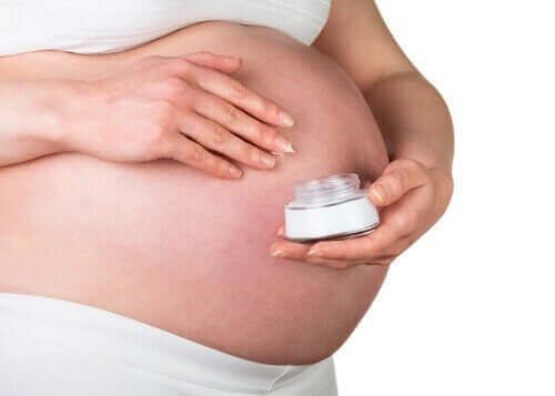 Gravid kvinde smører creme på mave