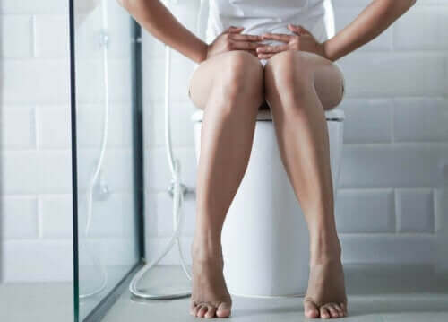 Kvinde sidder på toilet med ondt i maven
