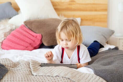 Barn med ipad i seng illustrerer for meget skærmtid