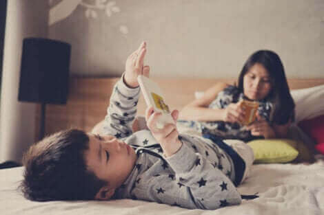Børn med smarttelefoner i seng illustrerer for meget skærmtid