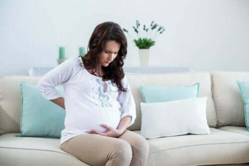 Gravid kvinde tager sig til maven, da hun oplever underlivssmerter under graviditet