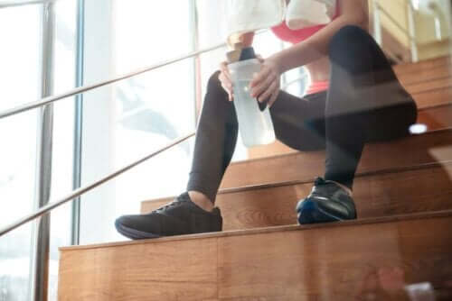 Kvinde sidder på trappe med vand efter træning