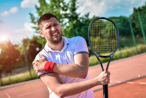 Mand, der dyrker tennis, tager sig til skulderen