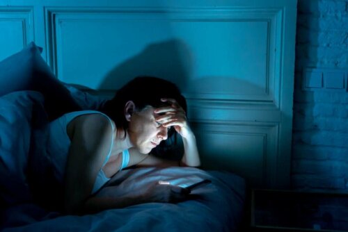 Kvinde med telefon i sengen