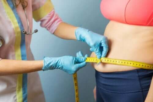 Læge måler kvindes omkreds om maven