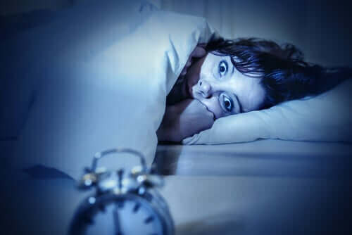 Søvnløs kvinde i seng oplever søvnparalyse