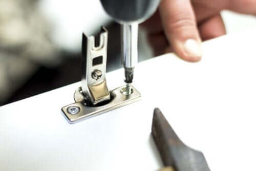 Person sætter nyt hængsel i møbel