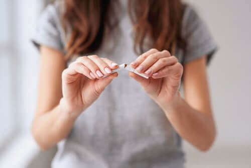 Kvinde knækker en cigaret som symbol for at stoppe rygning for at undgå fordøjelsesproblemer