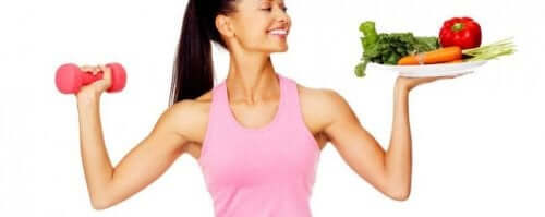 Kvinde, der holder en håndvægt og tallerken med grønt