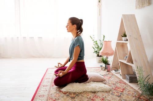Kvinde mediterer indenfor for at bekæmpe udmattethed fra psoriasisgigt