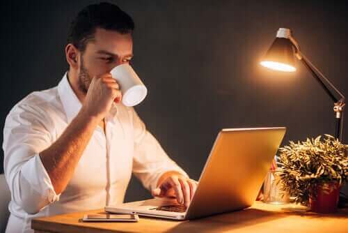 Mand arbejder hjemmefra med kaffe i hånden