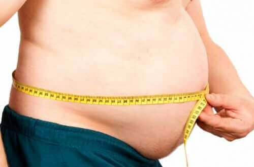 Person måler sin mave som symbol for forholdet mellem overvægt og de endokrine kirtler