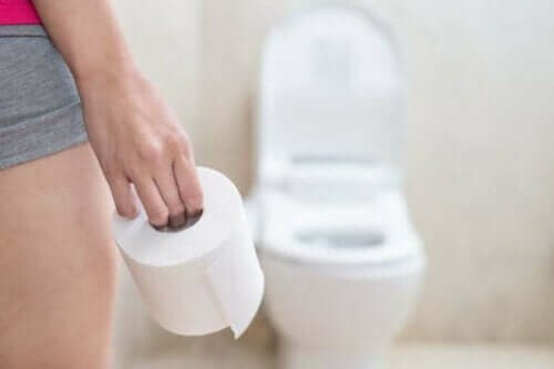 Kvinde med toiletpapir i hånden foran toilet