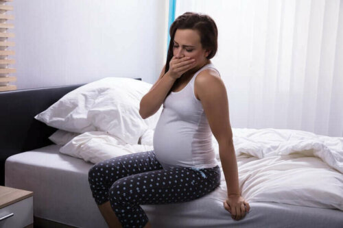 Træt gravid kvinde på kanten af seng