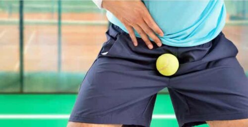 Tennisbold, der rammer mand i skridtet