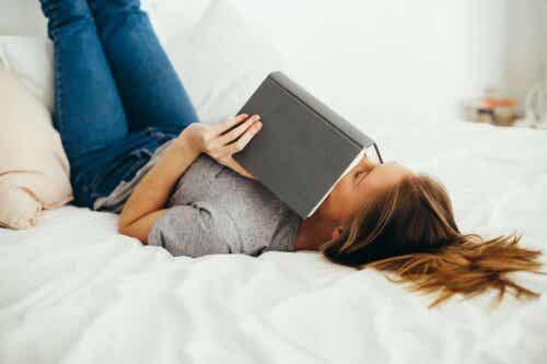 Kvinde læser i bog i sengen