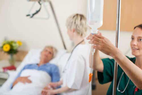 Sygeplejerske sætter drop op foran patient