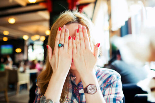 En kvinde gemmer sit ansigt bag hænderne grundet gelotofobi