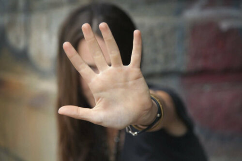 Kvinde siger stop ved at tage hånden op foran ansigtet