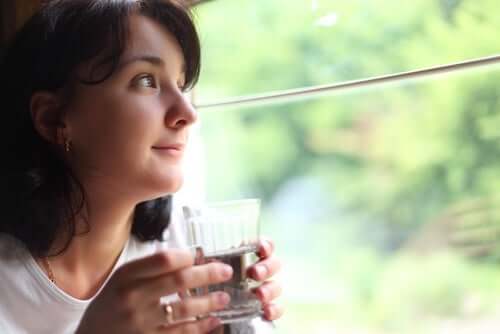 Kvinde ved vindue drikker vand