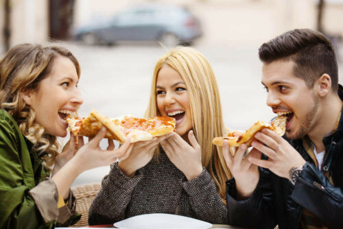 Venner spiser pizza sammen og nyder fordele ved at være udadvendt