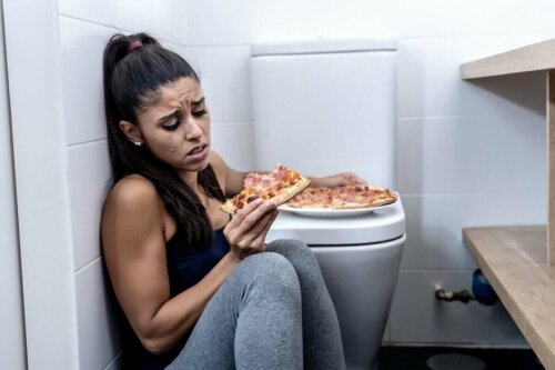 Kvinde med forstyrret spisning spiser pizza på toilet