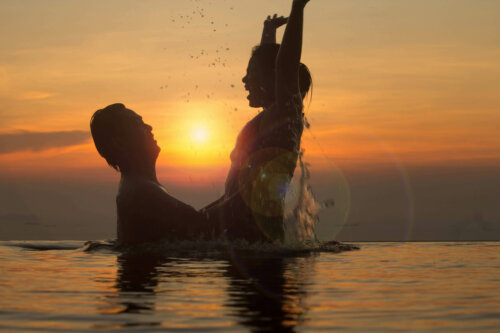 Par leger i en pool foran solnedgang