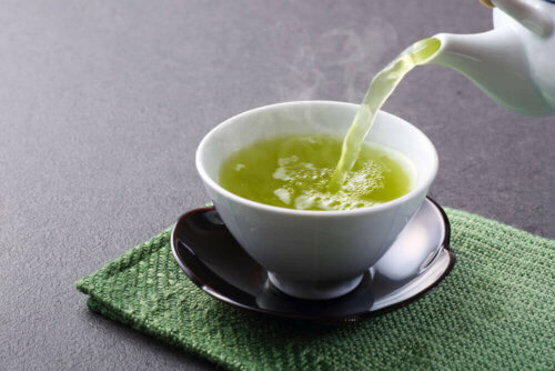 Grøn te hældes i kop