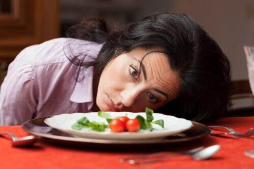 Sulten kvinde ser på tallerken med grøntsager