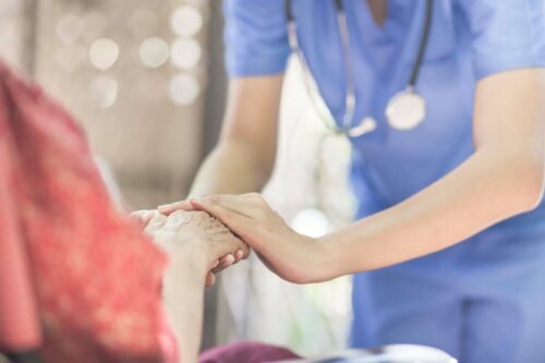 Sundhedsplejerske holder en ældre person i hånden