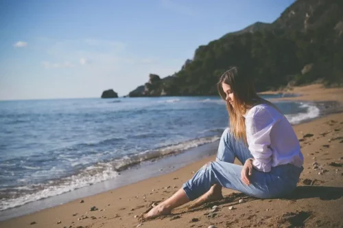 Kvinde sidder på strand