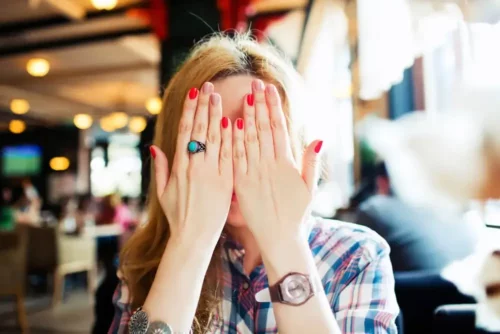 Kvinde med ekstrem generthed gemmer sit ansigt bag hænderne