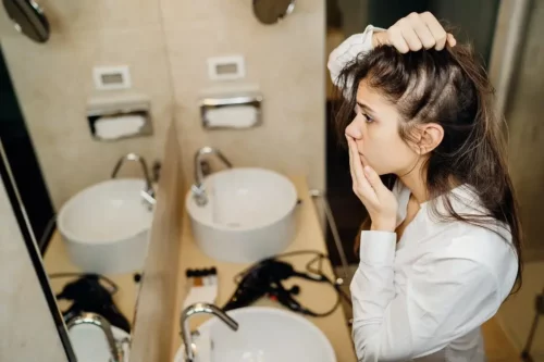 Kvinde ved spejl er bekymret over at miste hår