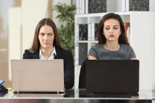 To kvinder ved computere ser mistænksomt på hinanden