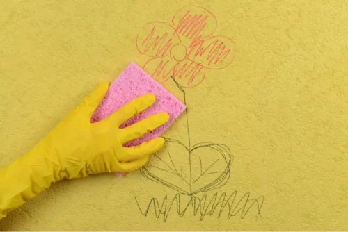 En person rengør kridt på en gul væg