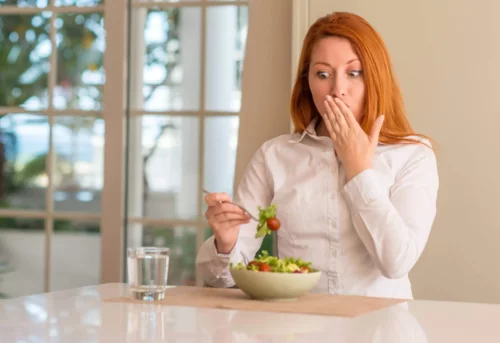 Kvinde med overrasket ansigtgsudtryk spiser en salat