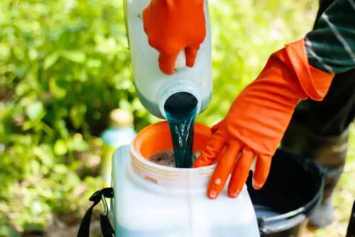 Person anvender handsker og hælder pesticider op