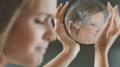 Kvinde undgår at se i et ødelagt spejl