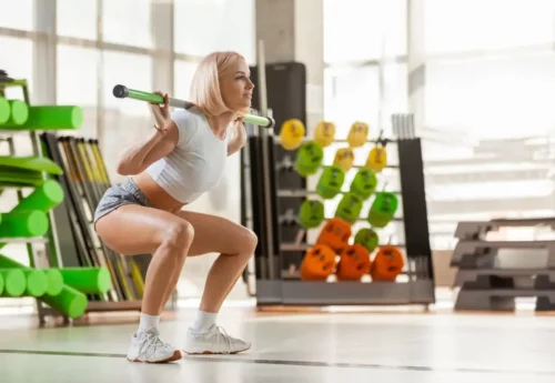 Kvinde squatter som en del af træning med vægtstænger
