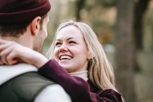 Smilende kvinde krammer mand og nyder øjenkontakt
