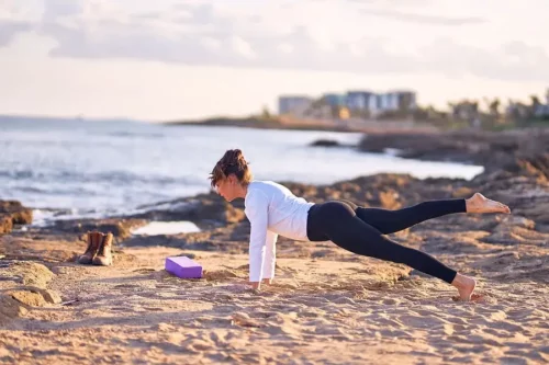 Kvinde dyrker yoga på strand
