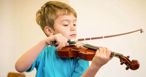 Dreng spiller violin i et multifunktionsrum