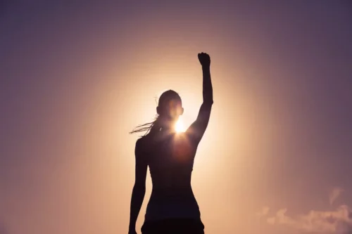 Kvinde med hånden op i luften som tegn på sejr
