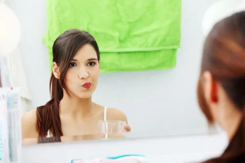 Kvinde bruger mundskyl for at bekæmpe bakteriel mundplak