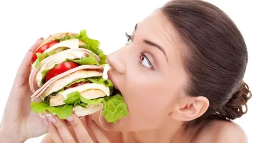 Kvinde spiser en stor sandwich
