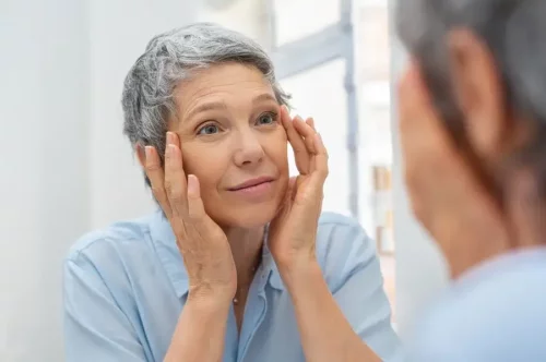 Kvinde ser i spejl og tjekker for tør hud hos ældre