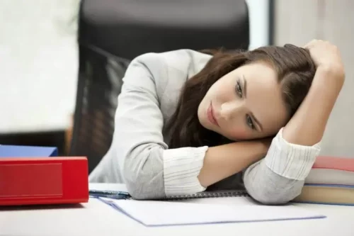En træt kvinde hviler sig på skrivebord