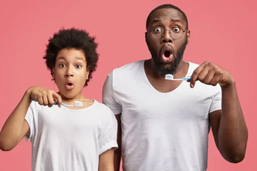 Far og barn med tandbørster og overraskede ansigtsudtryk
