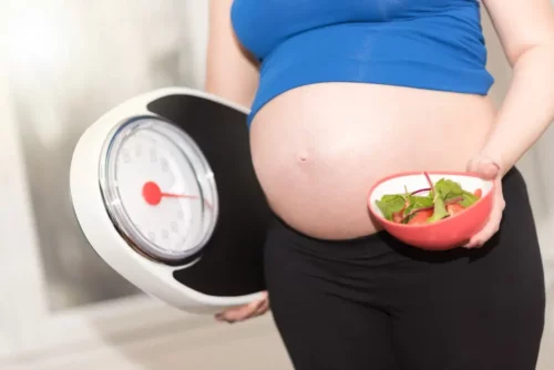 Gravid kvinde med salat og vægt repræsenterer faste under graviditet