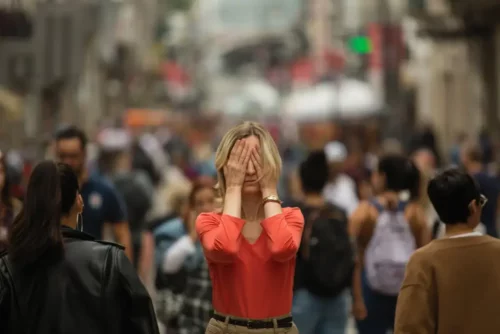 Kvinde skjuler ansigt, da hun får et angstanfald midt i menneskemængde